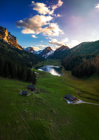 A farm in the valley next to a mountain lake