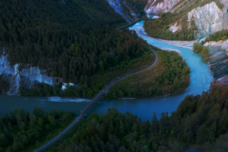 A river that runs in a S curve between the mountains,a railroad bridge crosses the riverの写真素材