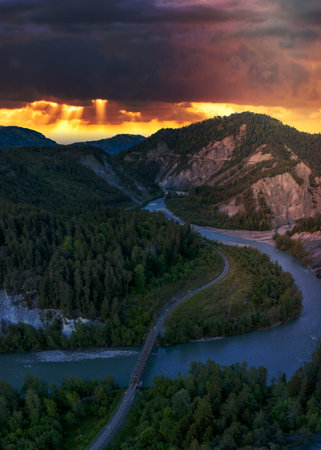 A river that runs in a S curve between the mountains,a railroad bridge crosses the riverの写真素材