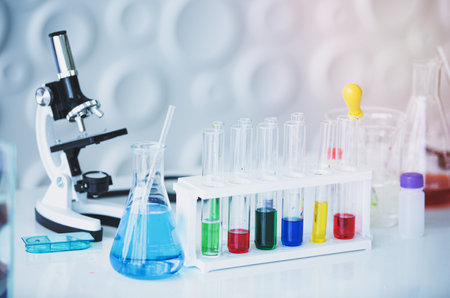 Microscope and colorful test tubes on table in Laboratory. Science chemistry concept. Blue toneの写真素材