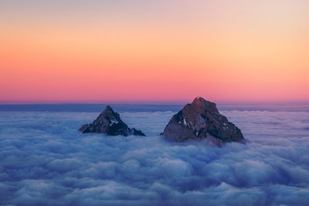 Two peaks rising from a sea of clouds during a sunsetの写真素材