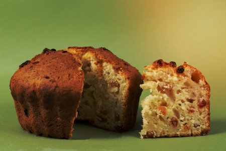 Classic cottage cheese pie with raisins.Cupcake with a cut piece on a green background.