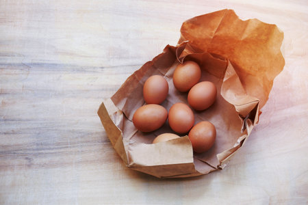 Brown egg in paper bag behind ,Fresh chicken eggs on wood table