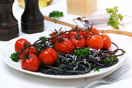 black pasta with baked tomatoes and parsley, close-upの写真素材