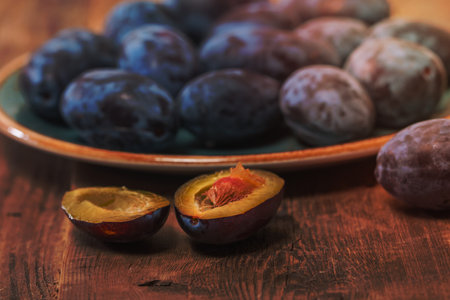 Fresh plums on a plate on wooden background