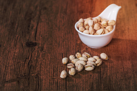 Pistachios in white bowl on wooden background