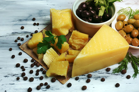 Parmesan cheese, fresh herbs and olives on wooden background
