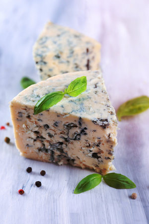 Tasty blue cheese with basil and spices on wooden tableの写真素材