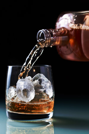 glass with whiskey and ice on a glass table