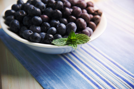 fresh organic blueberries on plate over white background retro kitchen tableの写真素材