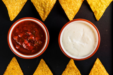 mexican street food nachos  with salsa and cream dip on black background