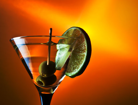 glass with martini and green olives on yellow background.の写真素材