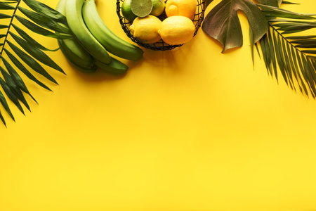 Border of fruits, citrus , tropical leaves on yellow. Summer concept. Top view with space for text.の写真素材