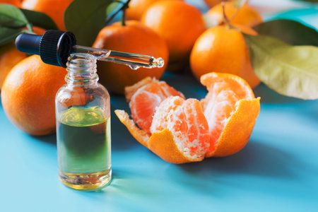 Essential oil of orange mandarin in glass bottle over pastel blue background. Spa and wellness concept.の写真素材