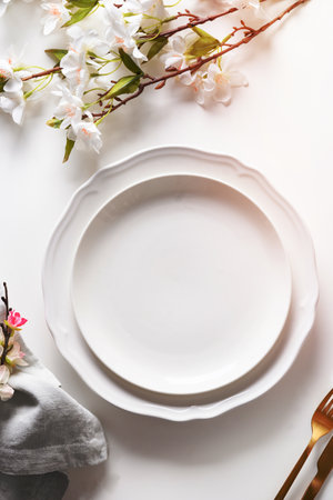 Spring Easter table setting with blooming flowers on white table. Top view. Vertical orientation....