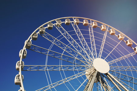 Part of a white Ferris wheel against a blue sky on a cloudless summer day.の写真素材