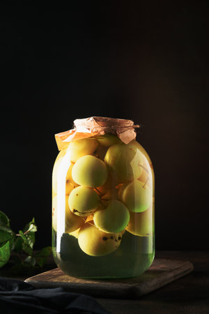Homemade canned apple compote in large glass jar on black table. Vertical format.の写真素材