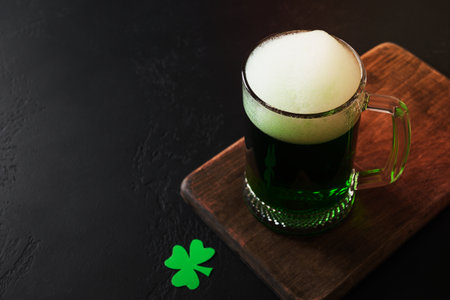 Patrick's day green beer in pint on black background. Copy space. Close up. Shamrock symbol of luck.
