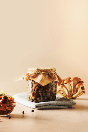 Homemade pickled honey Mushrooms in glass jar on a beige background. Vertical format. Close up.の写真素材