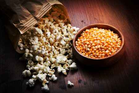 bowl of popcorn and kernelson a wooden tableの写真素材