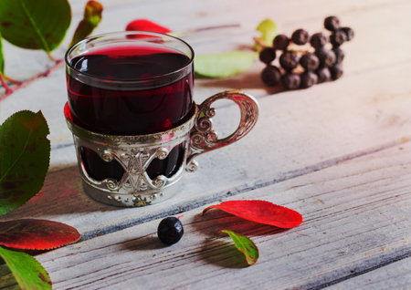 in a glass on a wooden background with branches chokeberryの写真素材