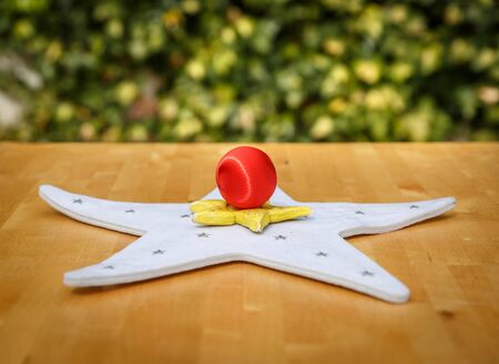 Two colored stars and a christmas ball on a table, with a green backgroundの写真素材