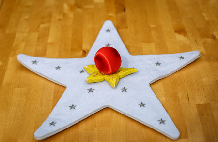 Two colored stars and a red christmas ball in the center, on a tableの写真素材