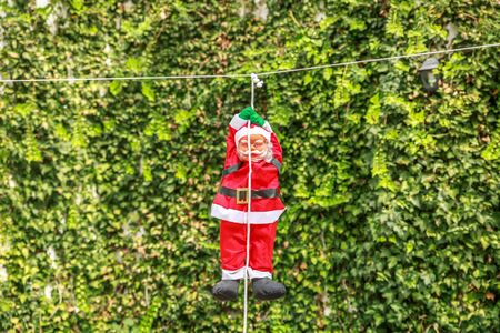 Santa claus hanging on a white rope, in the yard of a country houseの写真素材