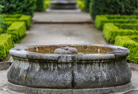 Stone water fountain in the middle of a beautiful botanical gardenの写真素材
