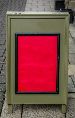 Green wooden poster with the central part in red, placed on the floor in the street at the entrance of a storeの写真素材