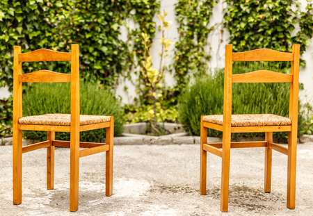 Two wooden and wicker chairs in a nice and cozy courtyardの写真素材