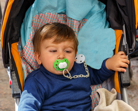 A cute boy with a pacifier in his baby carriageの写真素材