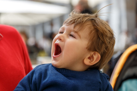 A cute and tender child screams while in the arms of an adultの写真素材