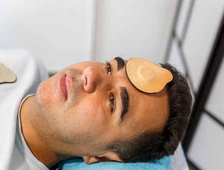 A patient lying down and relaxed on a stretcher with a magnet on his foreheadの写真素材