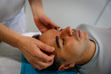A relaxed patient on a stretcher attended by his therapistの写真素材