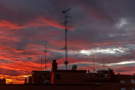 Impressive and red sunset in a city, rich in dark clouds, rays of lightの写真素材