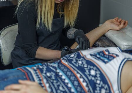 Blonde artist doing a tattoo in her small studioの写真素材