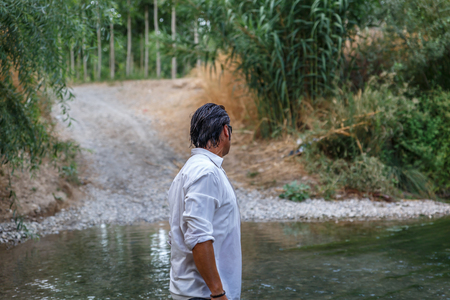 Mature man with wet hair is next to a streamの写真素材