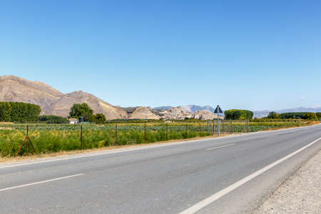 View of a long road with a beautiful landscape and a blue sky in the backgroundの写真素材