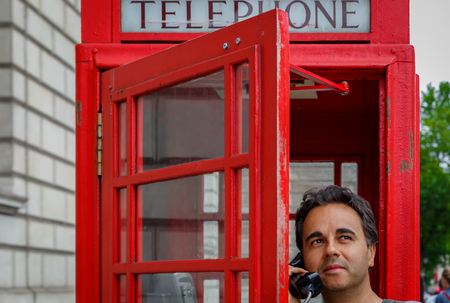 A man is talking in a typical London phone booth. United Kingdomの写真素材