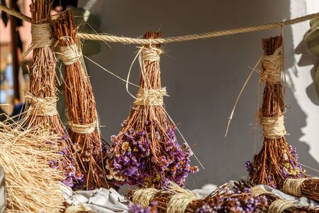 Several clusters of dried purple flowers hanging on a rope and exposed in a vintage marketの写真素材