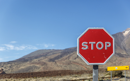 A large stop sign placed in an arid and volcanic landscapeの写真素材