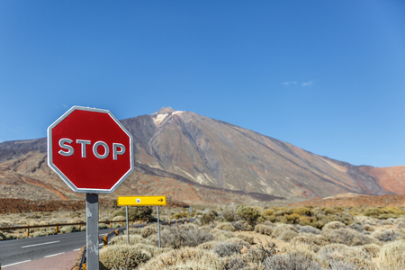 View of a volcanic landscape with a road and a large stop sign in the middleの写真素材