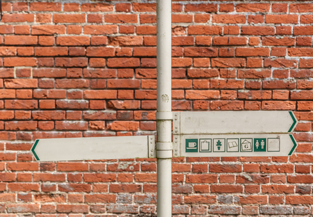 Signs on a pole indicating directions with a brick wall in the background, Englandの写真素材