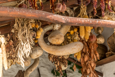 Cobs, dried fruits and vegetables hanging from an old wooden roof, in a large courtyard of a village in Spainの写真素材
