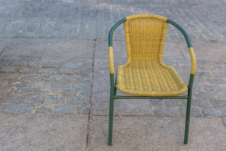 Simple and classic wicker chair with metal frame, alone in the streetの写真素材