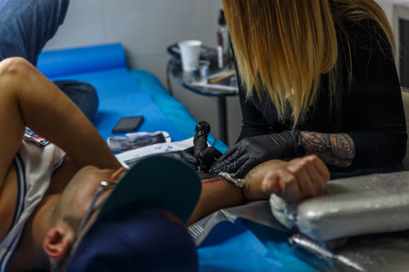 Close up view of the arm of a man who is being tattooed accurately in a small studio of a tattooistの写真素材