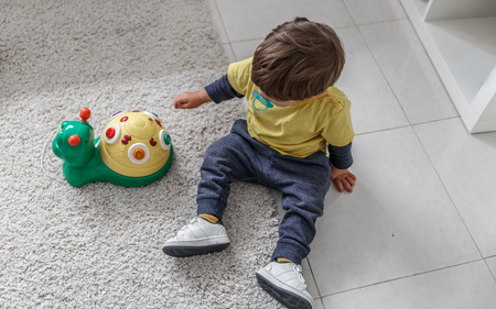 A beautiful child plays and enjoys his toys on the carpet in his bedroomの写真素材