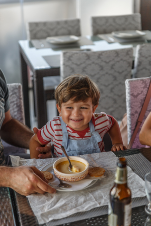 A cute little boy smiles very happy before eating in a restaurantの写真素材