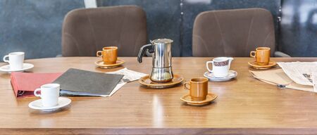 Table with several coffee cups and a coffee maker in the middle, typical of a meeting room in an...
